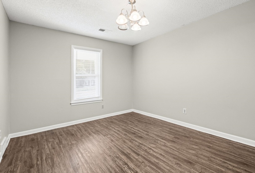 Spacious room featuring wood-finish flooring, light gray walls, and white baseboards