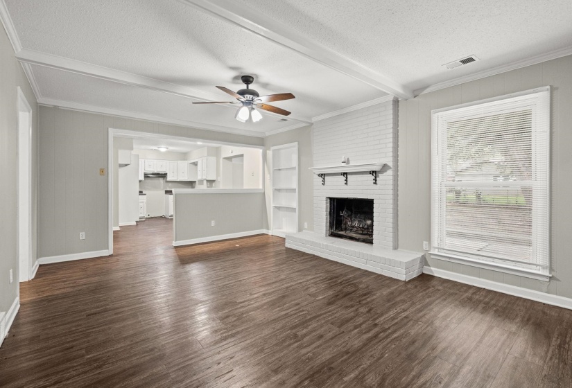 Living area featuring wood-finish flooring and a white painted brick fireplace with a mantel