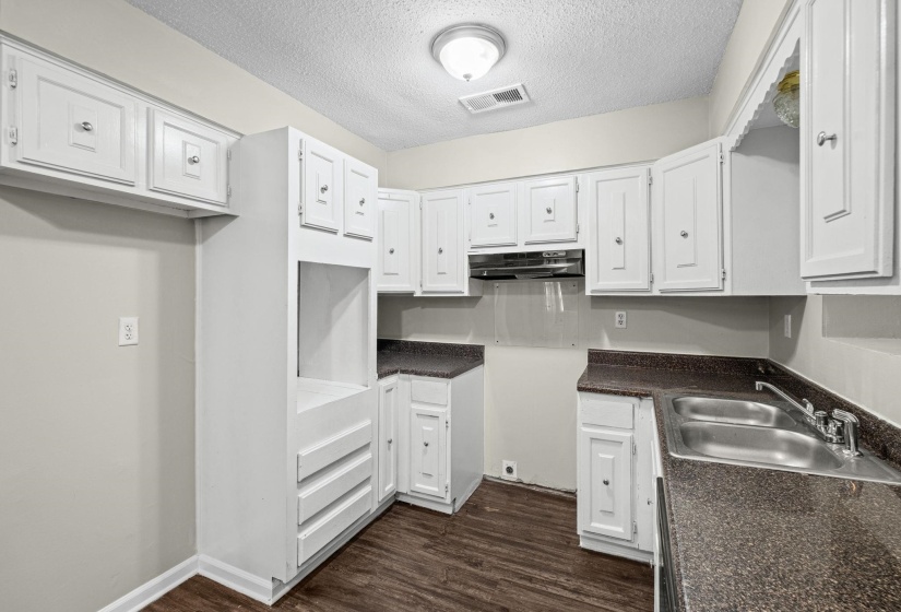 Kitchen featuring white shaker-style cabinetry, dark speckled countertops, a double basin stainless steel sink, and wood-finish flooring