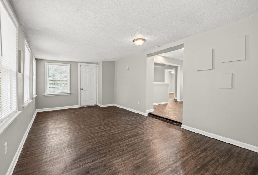 Spacious room featuring rich wood-finish flooring, light grey wall paint, and white trim throughout