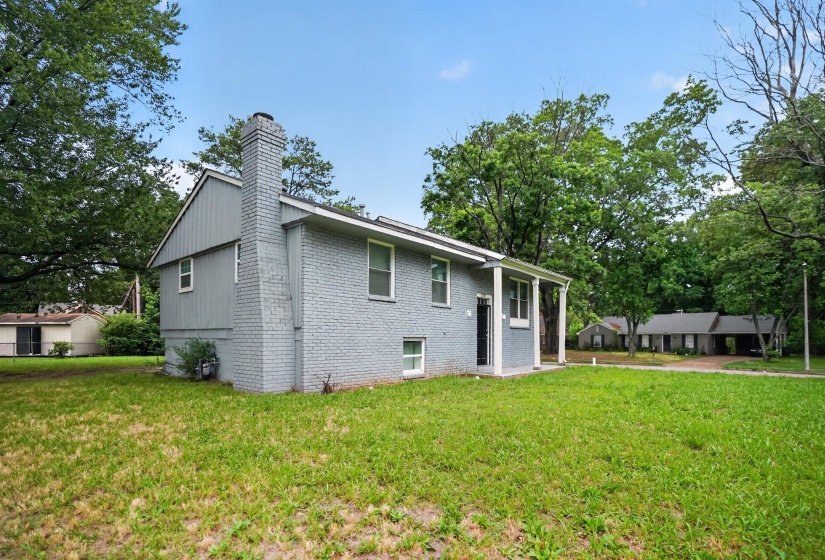 Exterior featuring painted brick and siding, a covered entry, and a prominent brick chimney