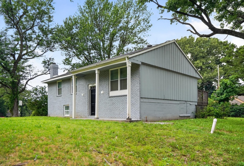 Split-level residence featuring a covered front porch, a contrasting dark entry door, and a brick exterior