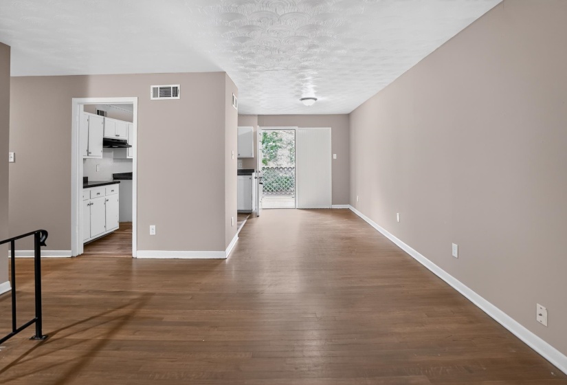 Spacious living area featuring wood-finish flooring, neutral wall paint, and white baseboards