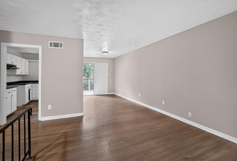 Spacious living area featuring wood-finish flooring, neutral wall paint, and white baseboards