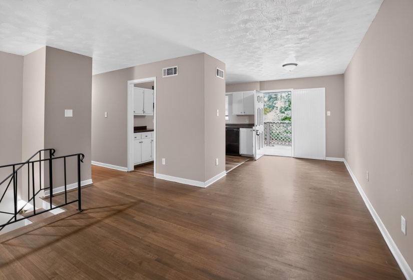 Open-concept living area featuring wood-finish flooring, neutral wall tones, and white baseboards