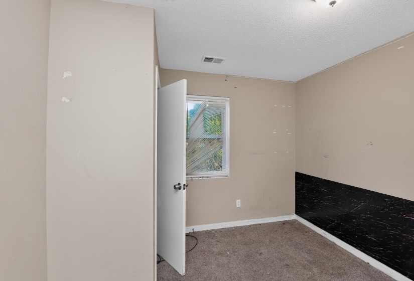 Room featuring a window with blinds, light-colored walls, a textured ceiling, and carpet flooring