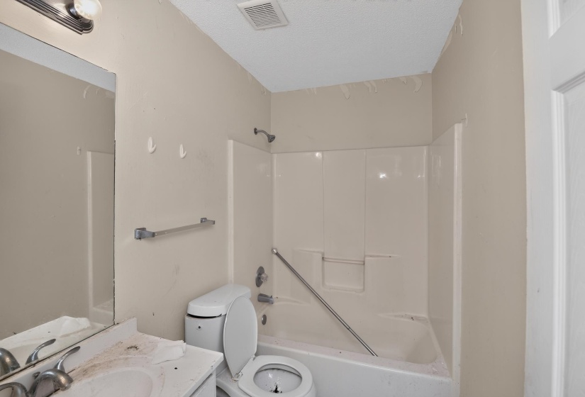 Bathroom featuring a built-in shower/tub combination with a white surround, wall-mounted showerhead, and grab bar