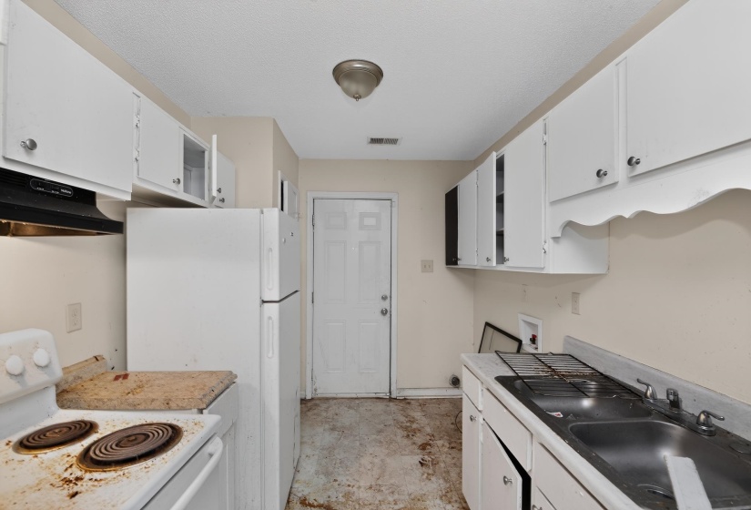Kitchen space featuring white cabinetry, a single-bowl sink, and a rear exterior door