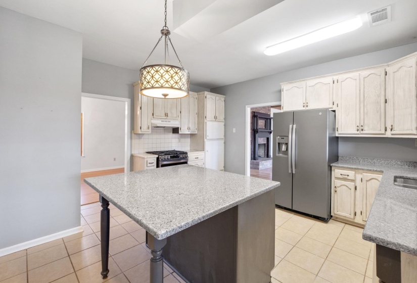 Kitchen featuring appliances with stainless steel finishes, light stone counters, pendant lighting, a center island, and a kitchen bar