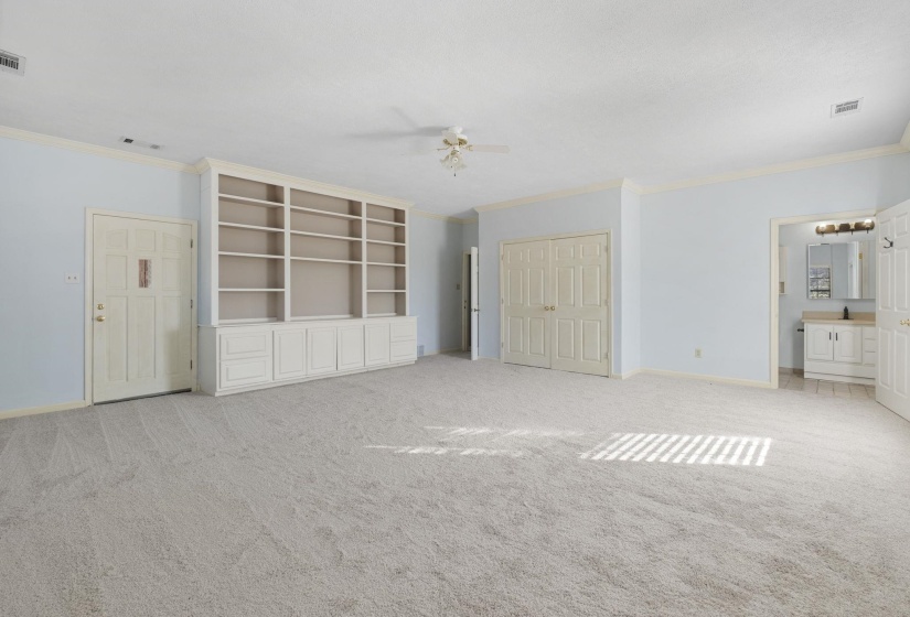 Unfurnished bedroom featuring crown molding, a closet, light carpet, a ceiling fan, and connected bathroom