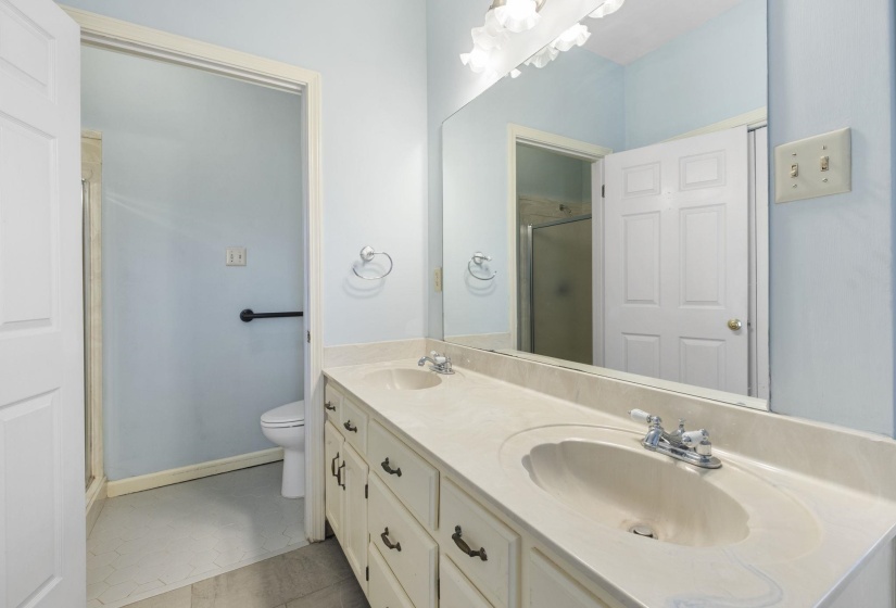 Bathroom featuring double vanity, a stall shower, and light tile patterned flooring