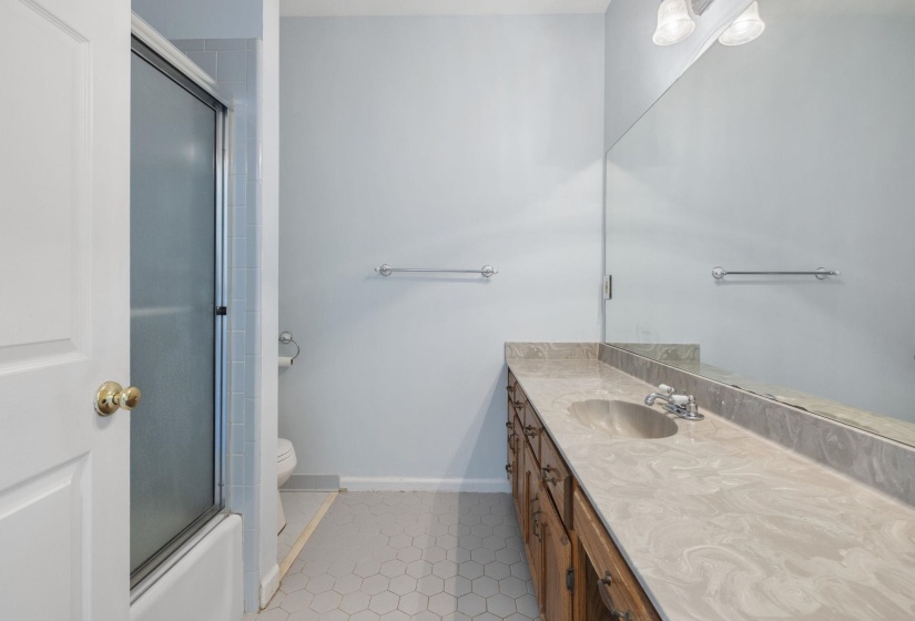 Bathroom with vanity, dark tile patterned flooring, and bath / shower combo with glass door