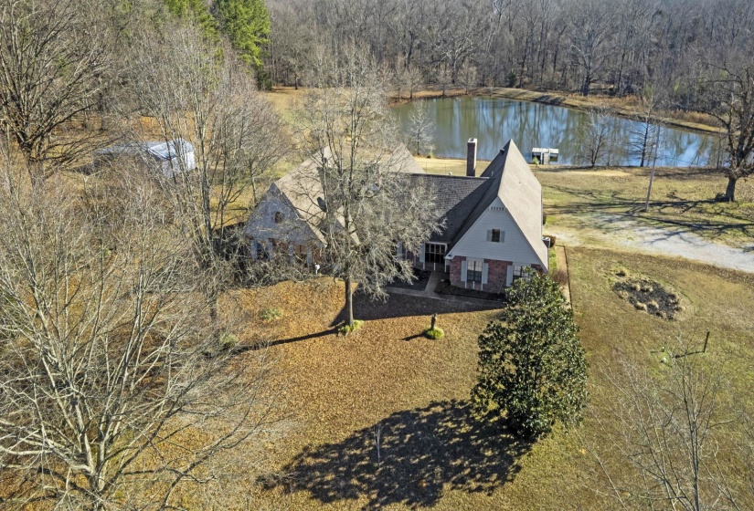 View of subject property with a nearby body of water and a forest