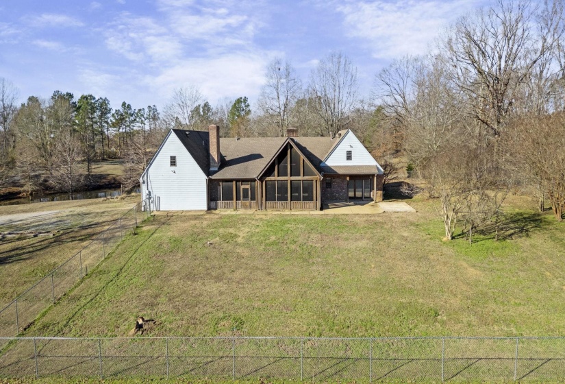 Back of house with a chimney and view of scattered trees