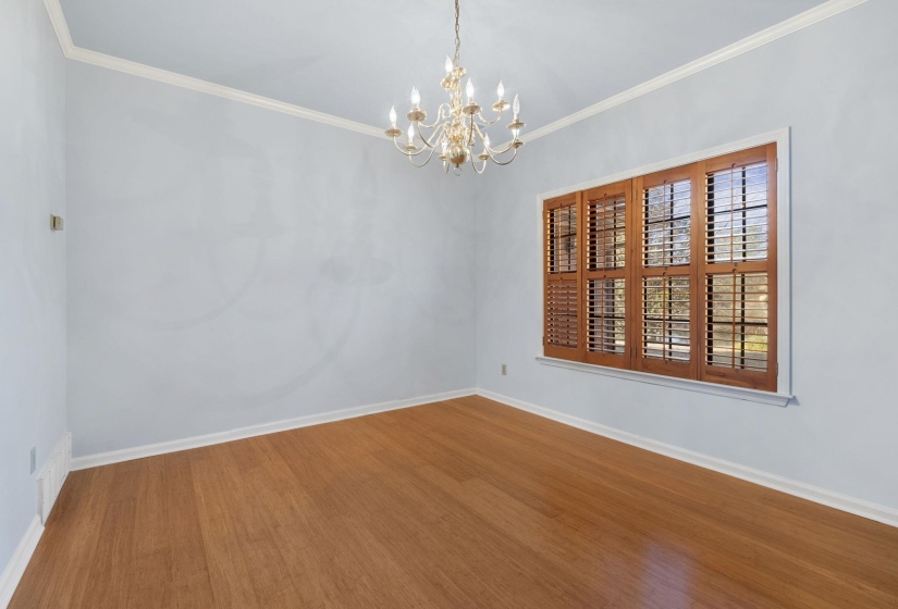 Spare room with wood finished floors, a chandelier, and crown molding