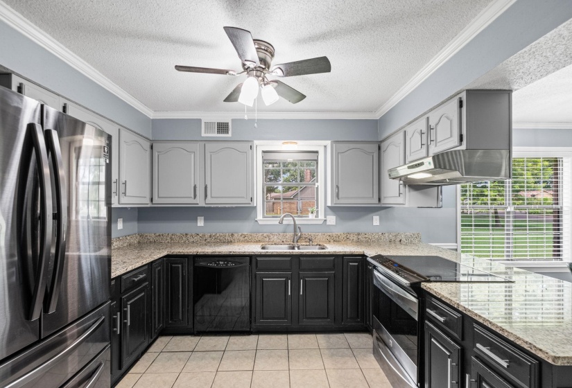 Kitchen featuring two-tone cabinetry, granite-style countertops, stainless steel appliances, a ceiling fan, and tile flooring