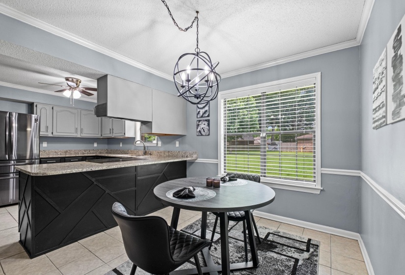 Eat-in kitchen featuring light blue walls with chair rail molding, a modern orb chandelier, and tile flooring
