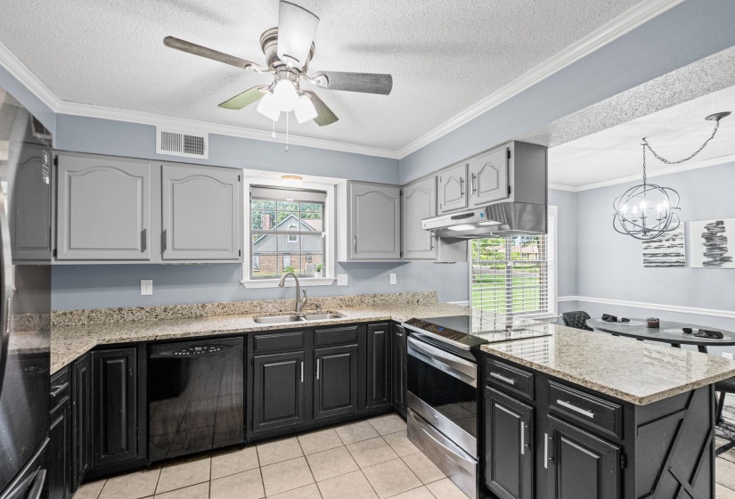 Kitchen featuring a center island, light-toned countertops, two-tone cabinetry, stainless steel appliances, and tile flooring