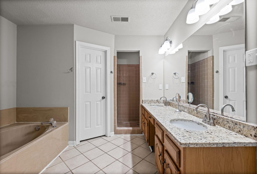 Bathroom featuring a dual vanity with granite countertops, wood cabinetry, and integrated sinks