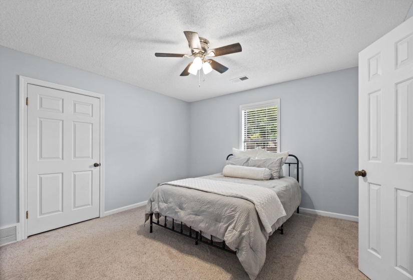 Bedroom featuring light blue walls, neutral carpet, and a ceiling fan with integrated lighting