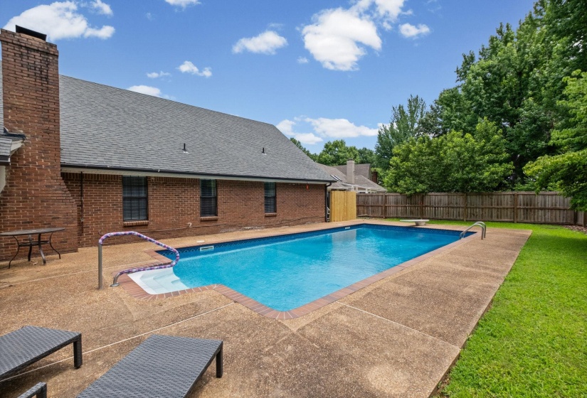 Rectangular inground swimming pool with integrated steps and a surrounding concrete patio