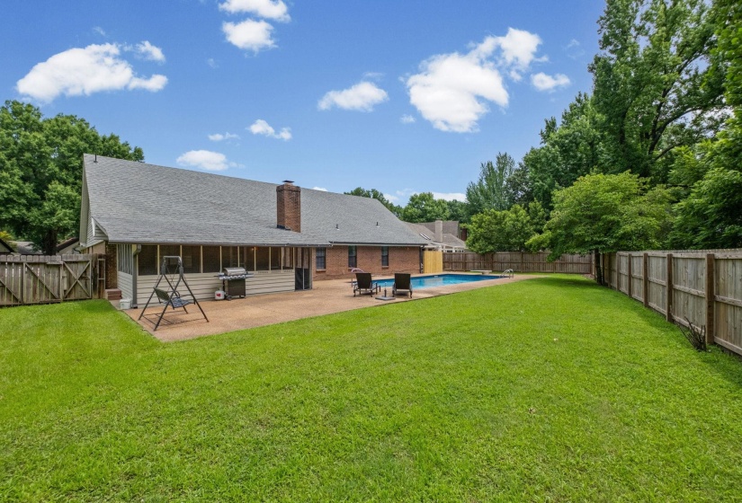 Expansive backyard featuring a large green lawn, private wooden fencing, and mature trees