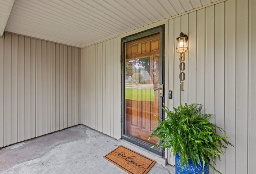 Covered entryway featuring vertical panel siding and a concrete floor