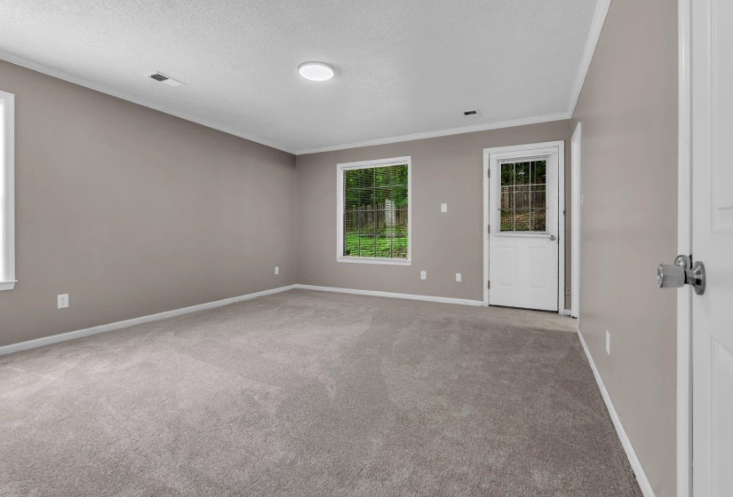 Spacious room featuring neutral carpeting, light neutral wall paint, and white trim