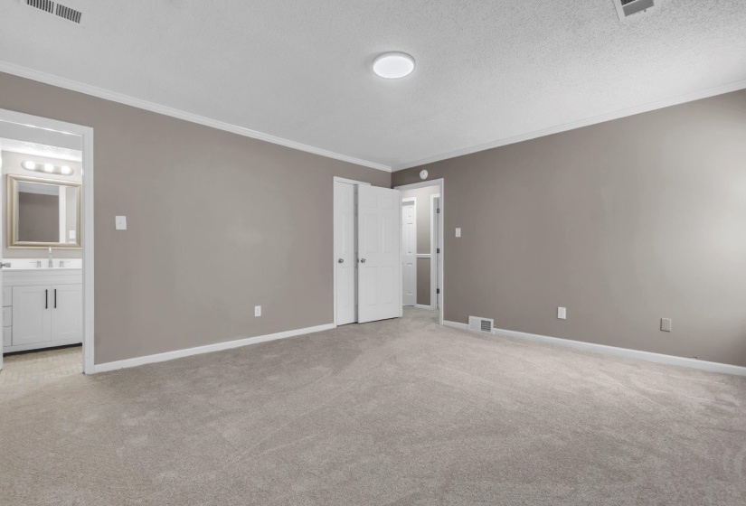 Spacious room featuring neutral paint, gray carpet, crown molding, and two panel doors