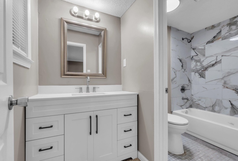 White shaker-style vanity with a light-toned countertop, rectangular sink, and polished chrome faucet