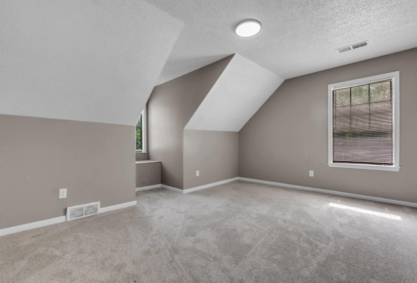 Carpeted room featuring sloped ceilings, two windows with blinds, and recessed lighting
