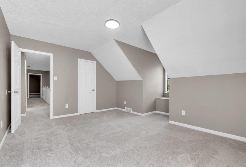 Spacious room featuring sloped ceilings, light gray wall paint, recessed lighting, and soft carpet flooring
