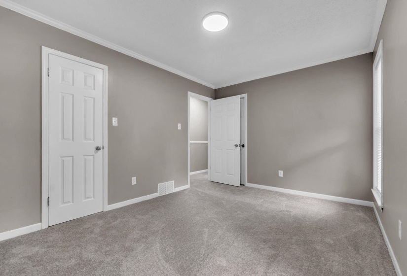 Carpeted room featuring neutral wall tones, white trim, a flush-mount ceiling light, and a paneled interior door