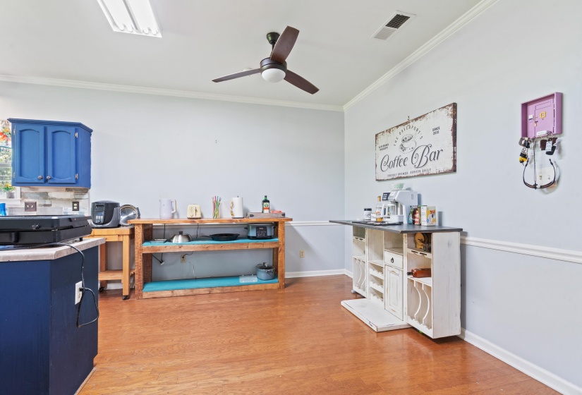 Spacious room featuring wood-finish flooring, a ceiling fan, and crown molding