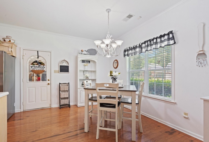 Bright dining area featuring wood-finish flooring, a multi-pane window with blinds, and a white chandelier