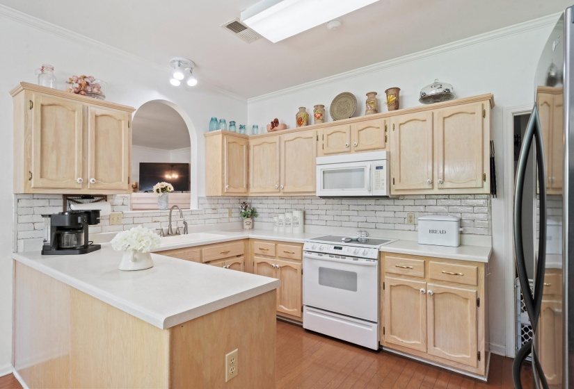 Kitchen featuring light-finish cabinetry, white countertops, subway tile backsplash, and white appliances including a built-in microwave and range