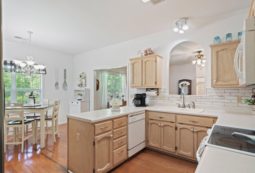 Kitchen featuring light wood-finish cabinetry, white countertops, and a white subway tile backsplash