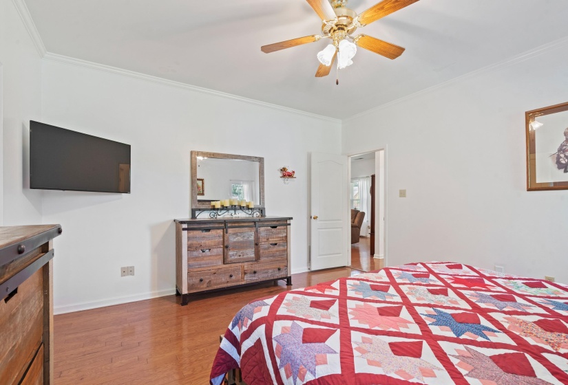 Hardwood-finish flooring throughout the room, complemented by a ceiling fan with integrated lighting