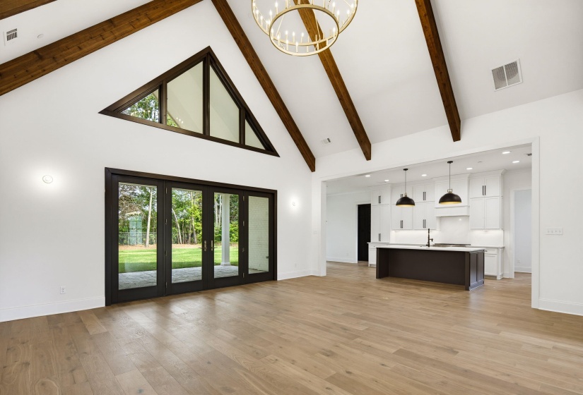 Vaulted ceiling featuring exposed wood beams and a contemporary chandelier