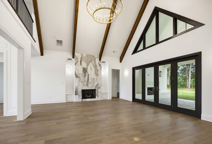 Great room featuring a vaulted ceiling with exposed wood beams and a contemporary chandelier