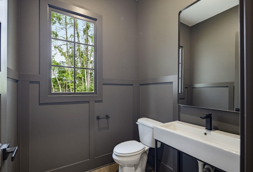 Powder room featuring board and batten walls, a single-hung window with grilles, a floating vanity with a vessel sink, and a matte black faucet