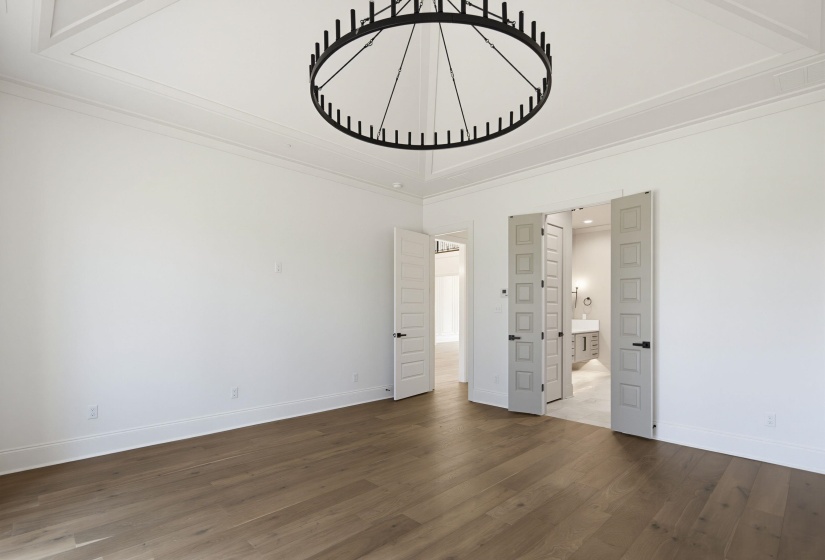 Spacious room featuring wood-finish flooring and a coffered ceiling with a prominent black chandelier