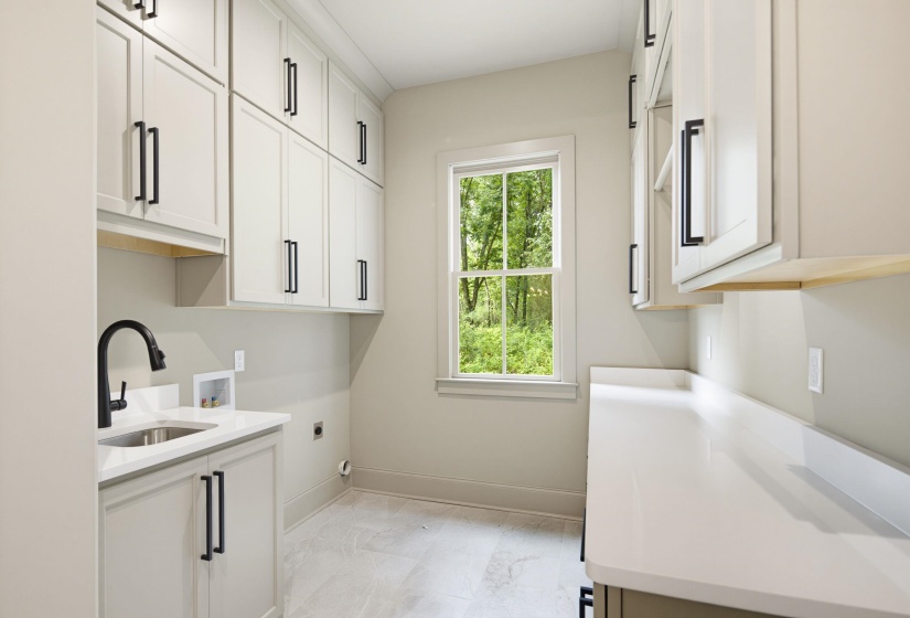 Utility room featuring extensive white cabinetry with matte black hardware
