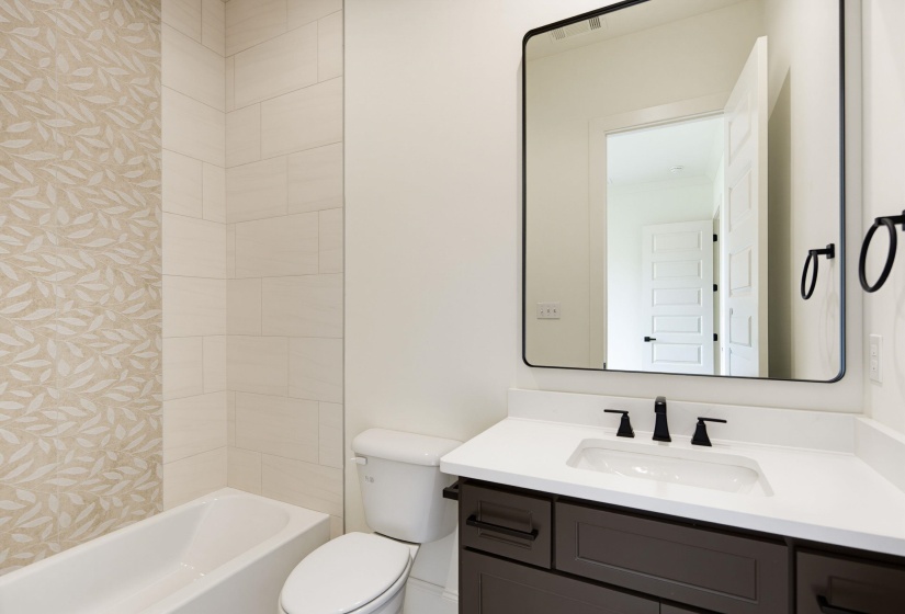 Bathroom featuring a white bathtub, a toilet, and a vanity with a white countertop