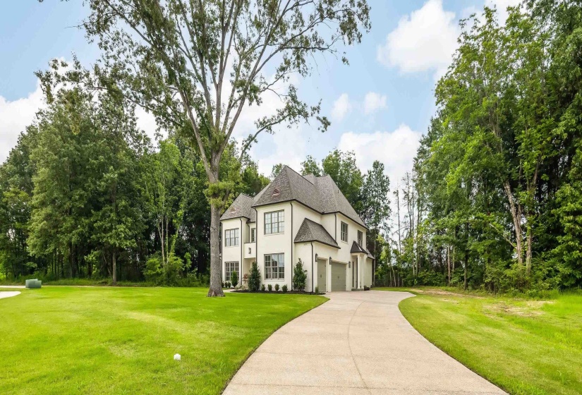 Stately residence featuring a light-colored exterior, dark shingle roof, multiple gables, and a prominent front entry