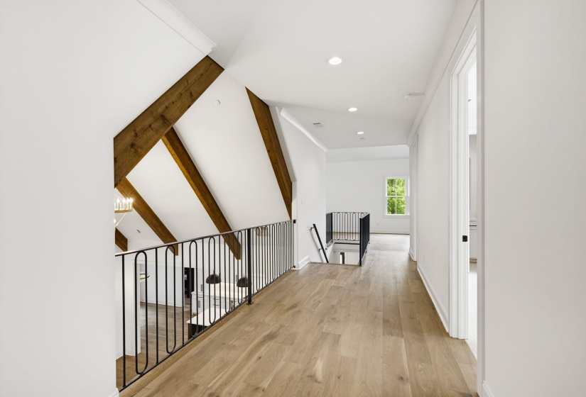 Second-story hallway featuring wood-finish flooring, recessed lighting, and a white color palette