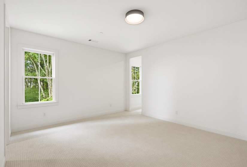 Room featuring two windows with white trim, light-toned carpet flooring, white walls, and a circular flush-mount ceiling light