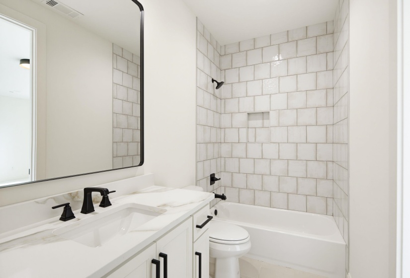 Bathroom featuring a white vanity with an integrated sink, black fixtures, and a framed mirror