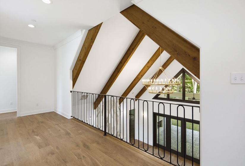 Bright loft space featuring wood-finish flooring and a black iron railing overlooking the lower level