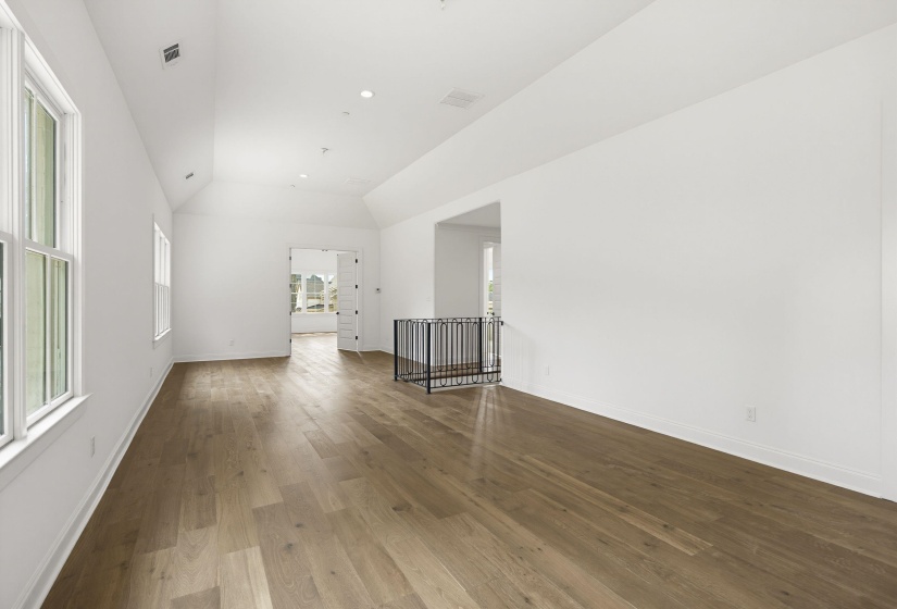 Spacious interior with wood-finish flooring, vaulted ceilings, recessed lighting, and multiple windows
